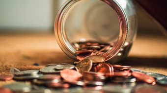 Coins spilling out of a glass jar.