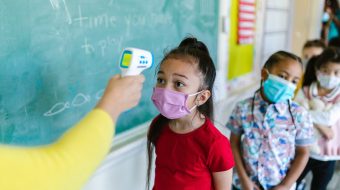 Children line up in a classroom to get tested for Covid.