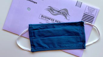 A medical mask laying on top of a voter mailing.