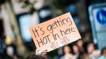 Climate strike sign reading "It's getting HOT in here" with flames