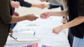 Voting volunteers handing voting materials to voters across the table